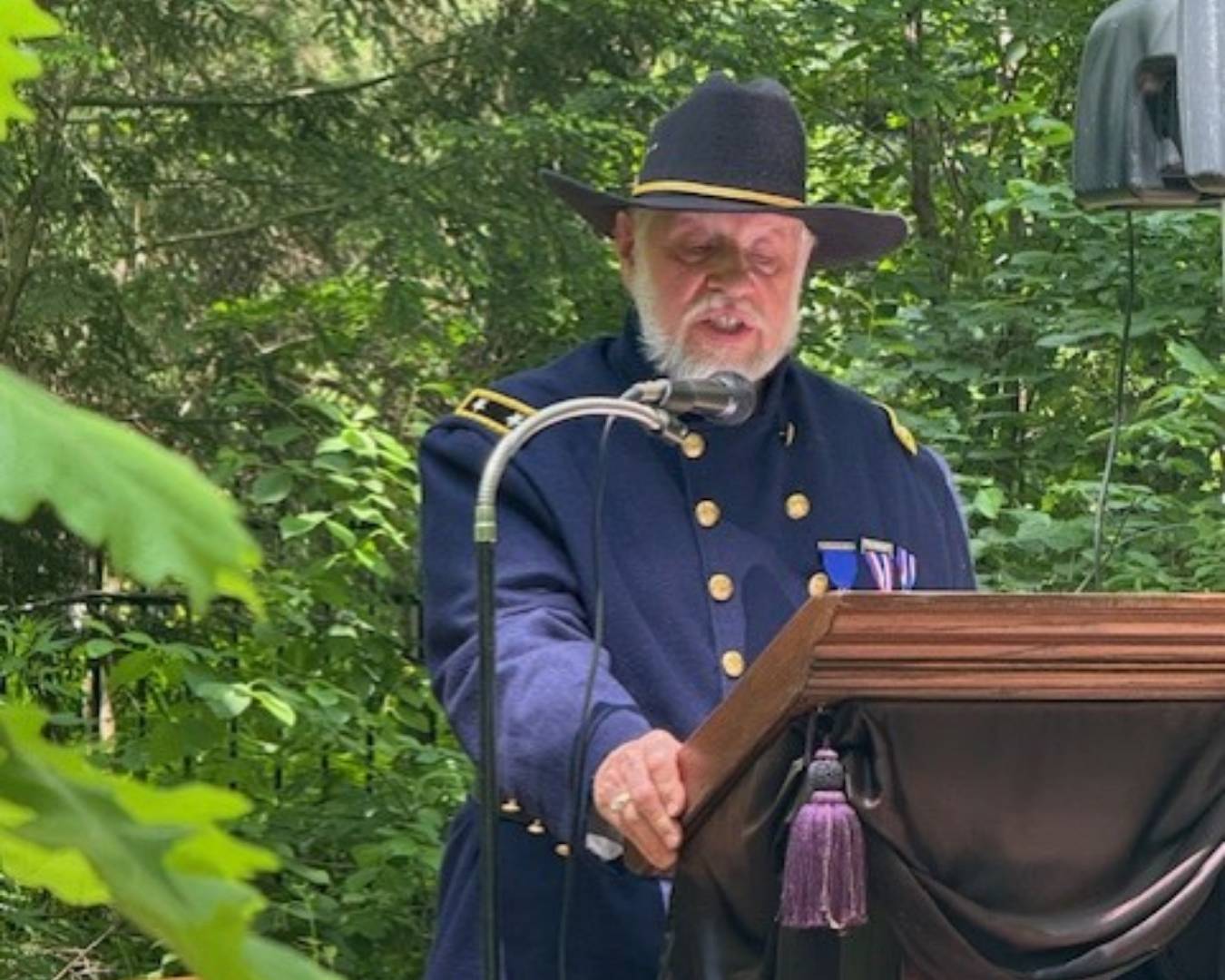 Mike Zafran Bio Photo at cemetery speaking at podium 